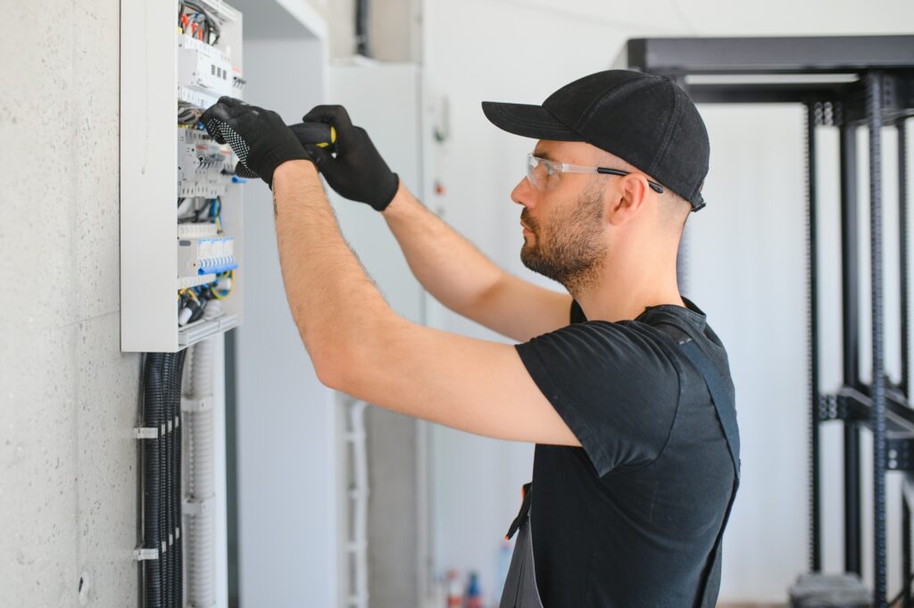 Male electrician working in a switchboard with fuses