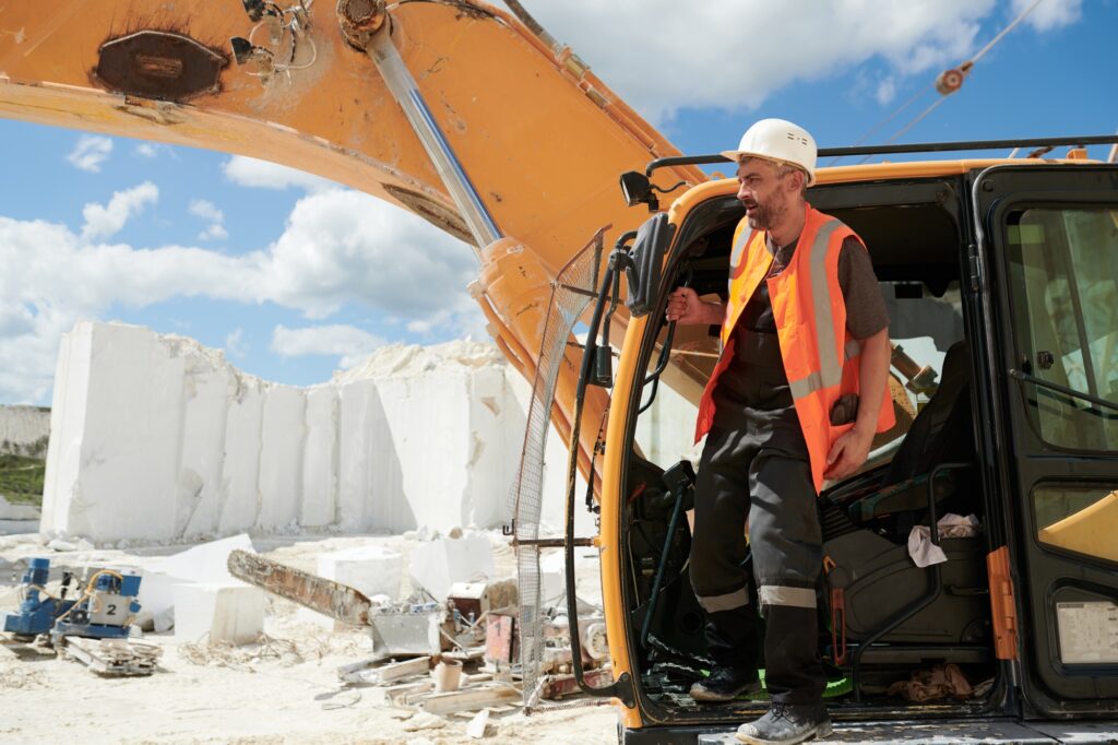 Middle aged foreman or driver of construction machine standing in open door